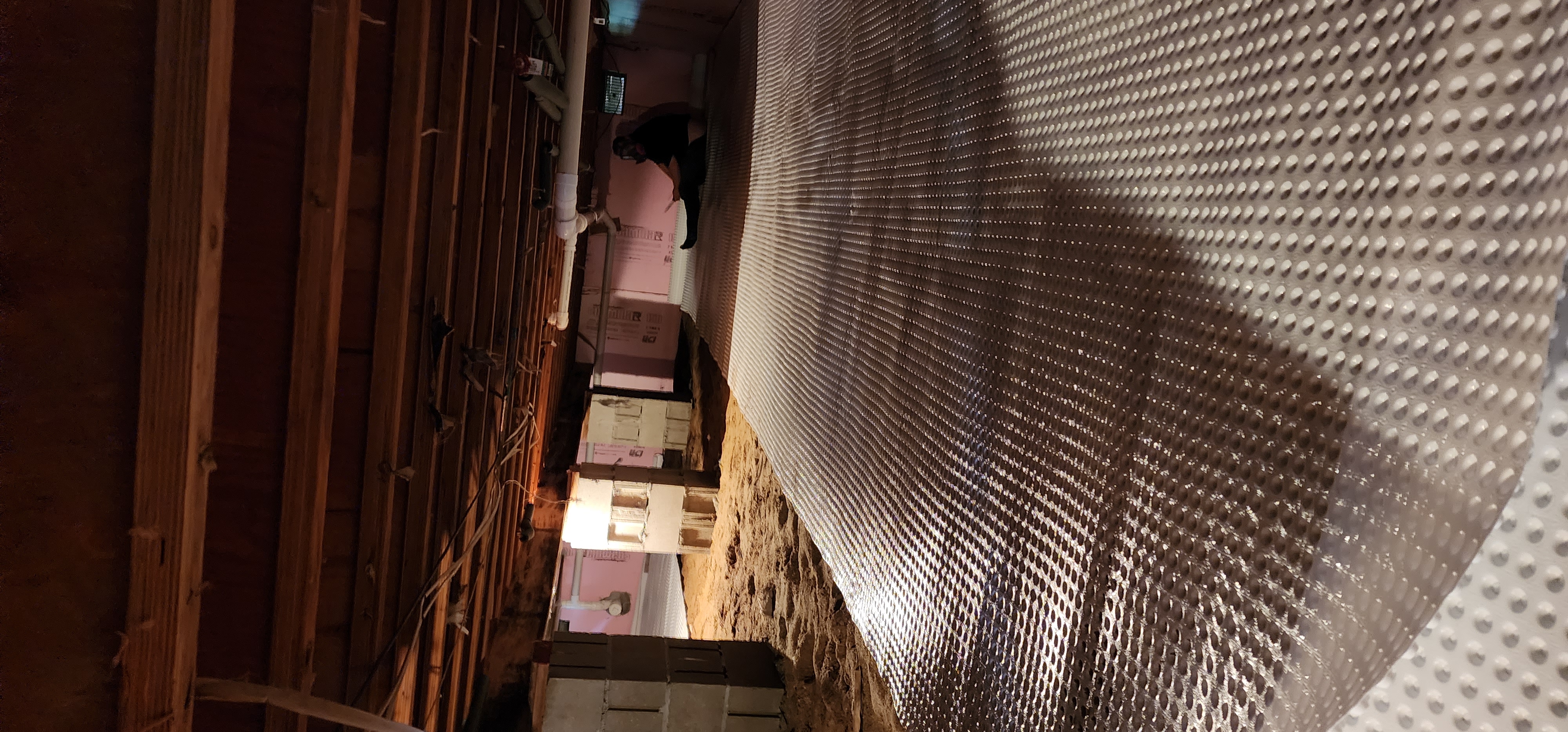 Crawlspace encapsulation process with plastic sheets and vapor barriers in a home.