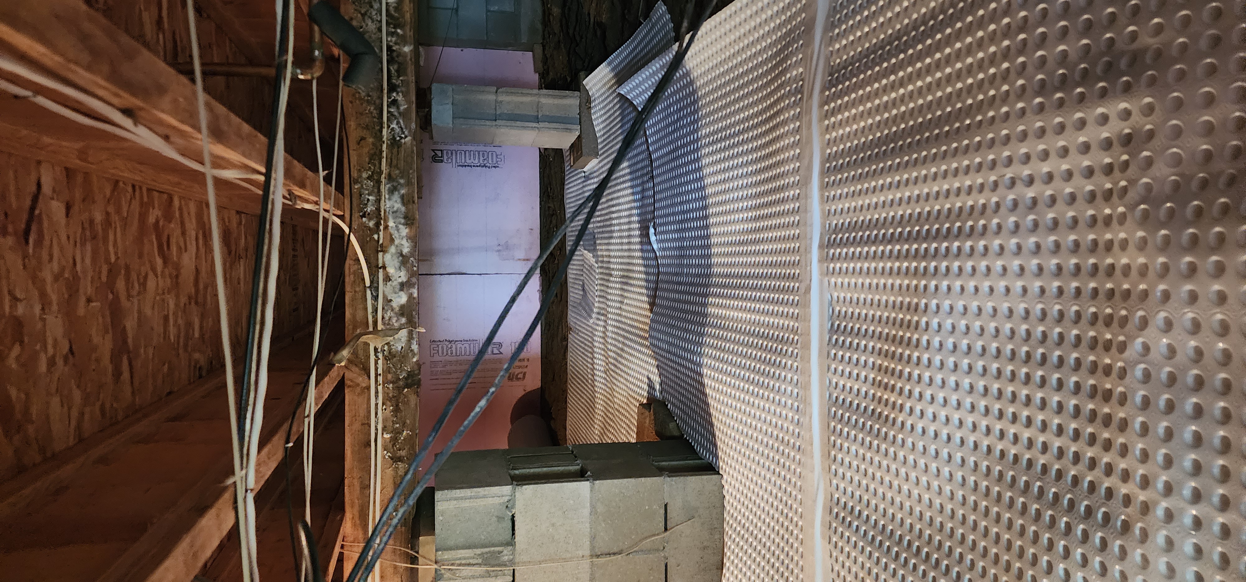 Crawlspace encapsulation process in a home in Manistee, Michigan, illustrating sealing and insulation methods.