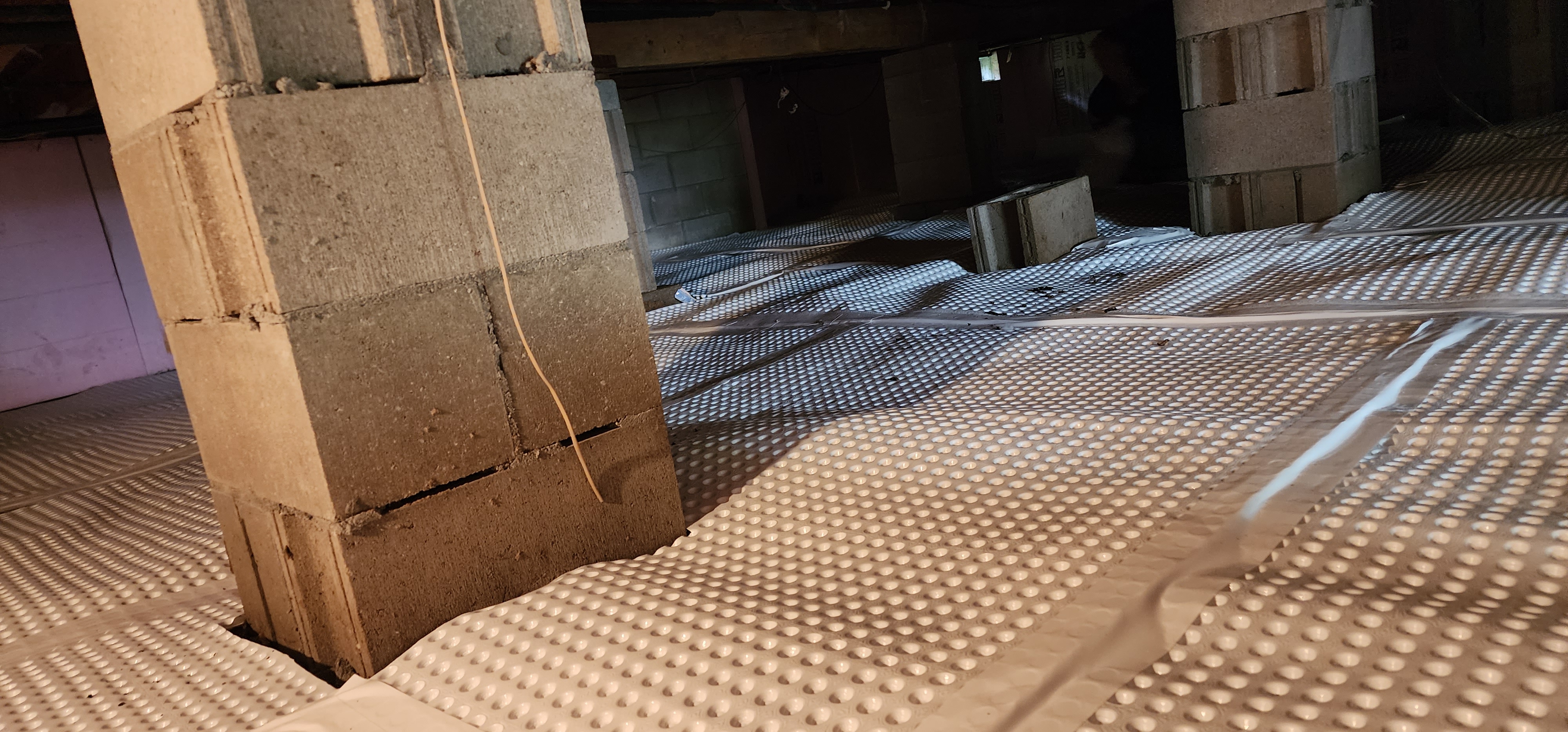 Crawlspace encapsulation process in a Marne, Michigan home showing sealed vapor barriers and dehumidifiers.