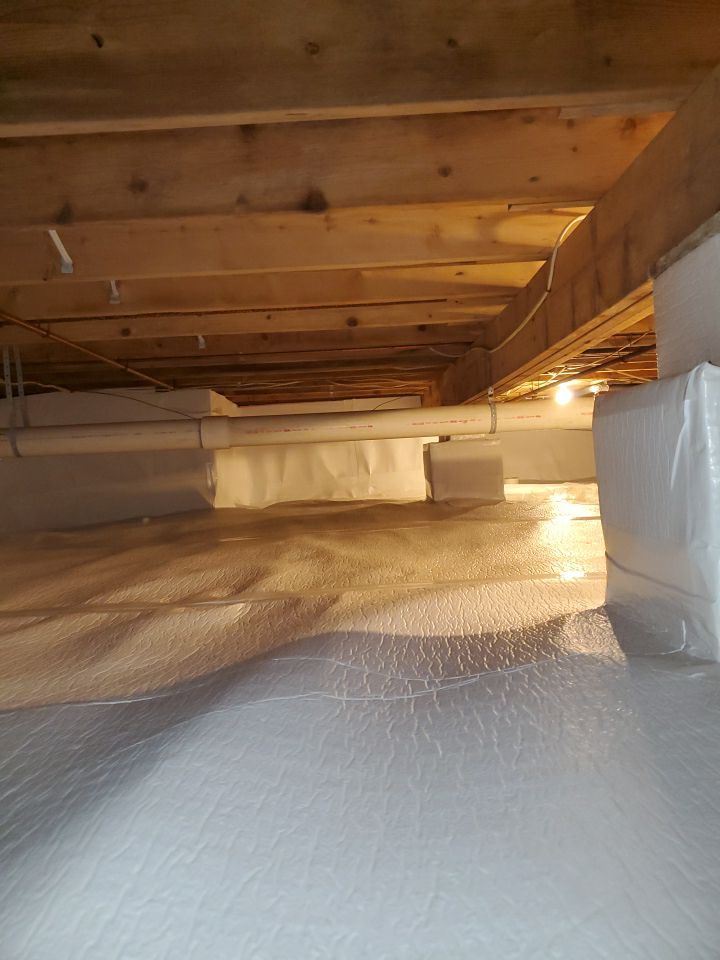 Crawlspace encapsulation process showing sealed vapor barrier in a dark crawlspace