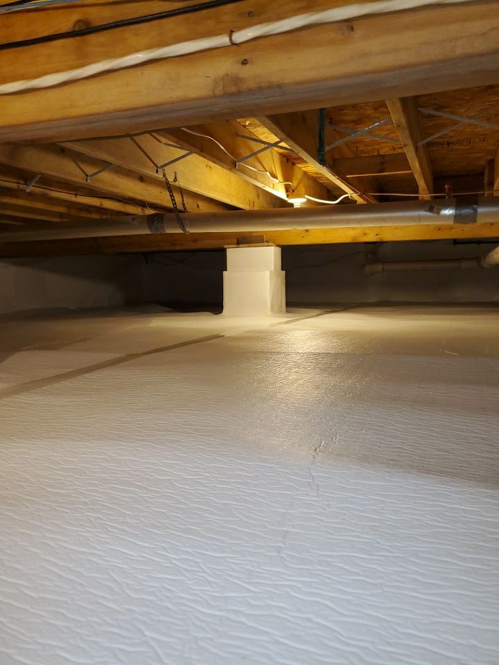 A professionally encapsulated crawlspace in a Mackinaw City home, showcasing clean white barriers and a controlled environment.